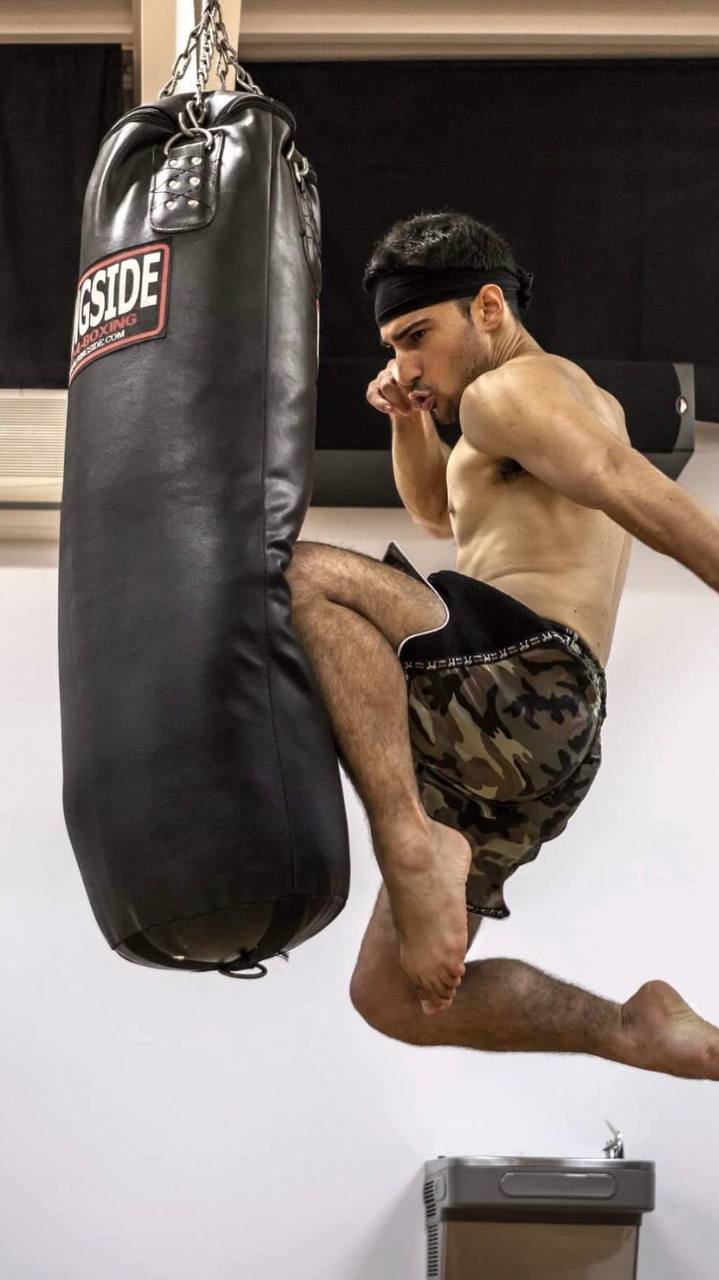 Martial artist delivering a flying knee to a heavy bag